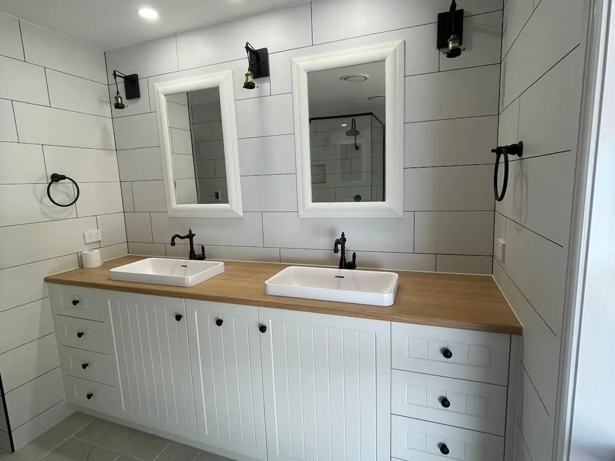 Main bathroom with a double vanity, wood-grain benchtop, two white-framed mirrors, black tapware and white subway-style wall tiles, Amaroo home