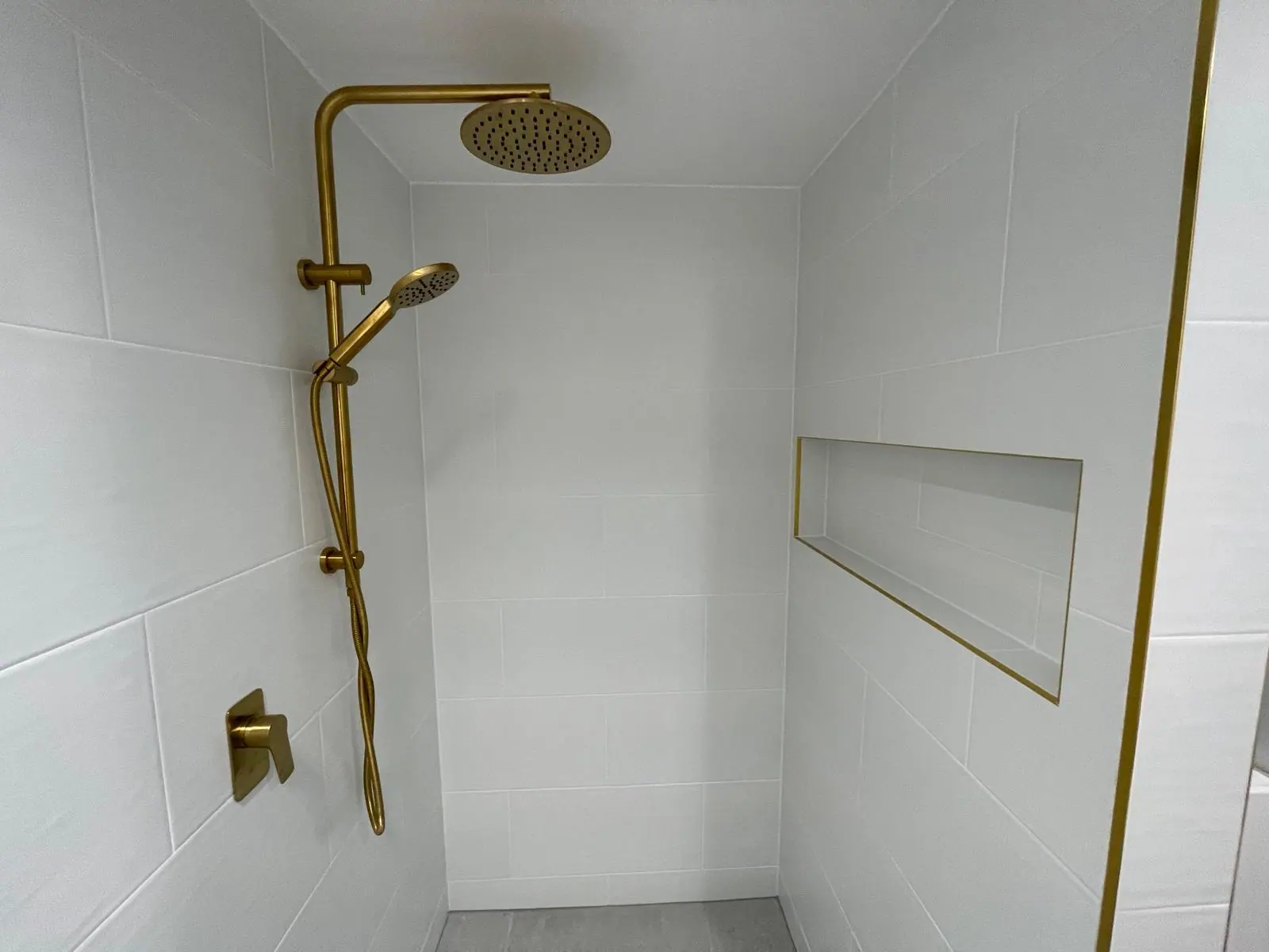 Walk-in shower with a brushed-brass rail shower and mixer, white wall tiles and a brass-trimmed recessed niche, Calwell home