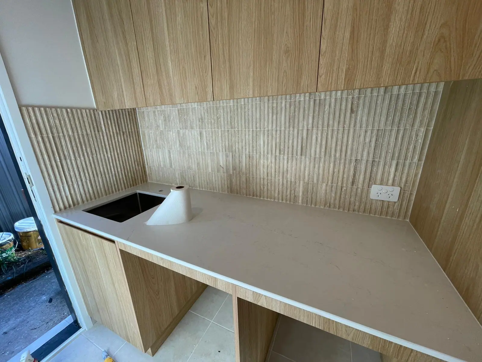 Laundry bench with timber-look cabinetry, a stone benchtop, an undermount sink and a fluted-tile splashback, Wanniassa home